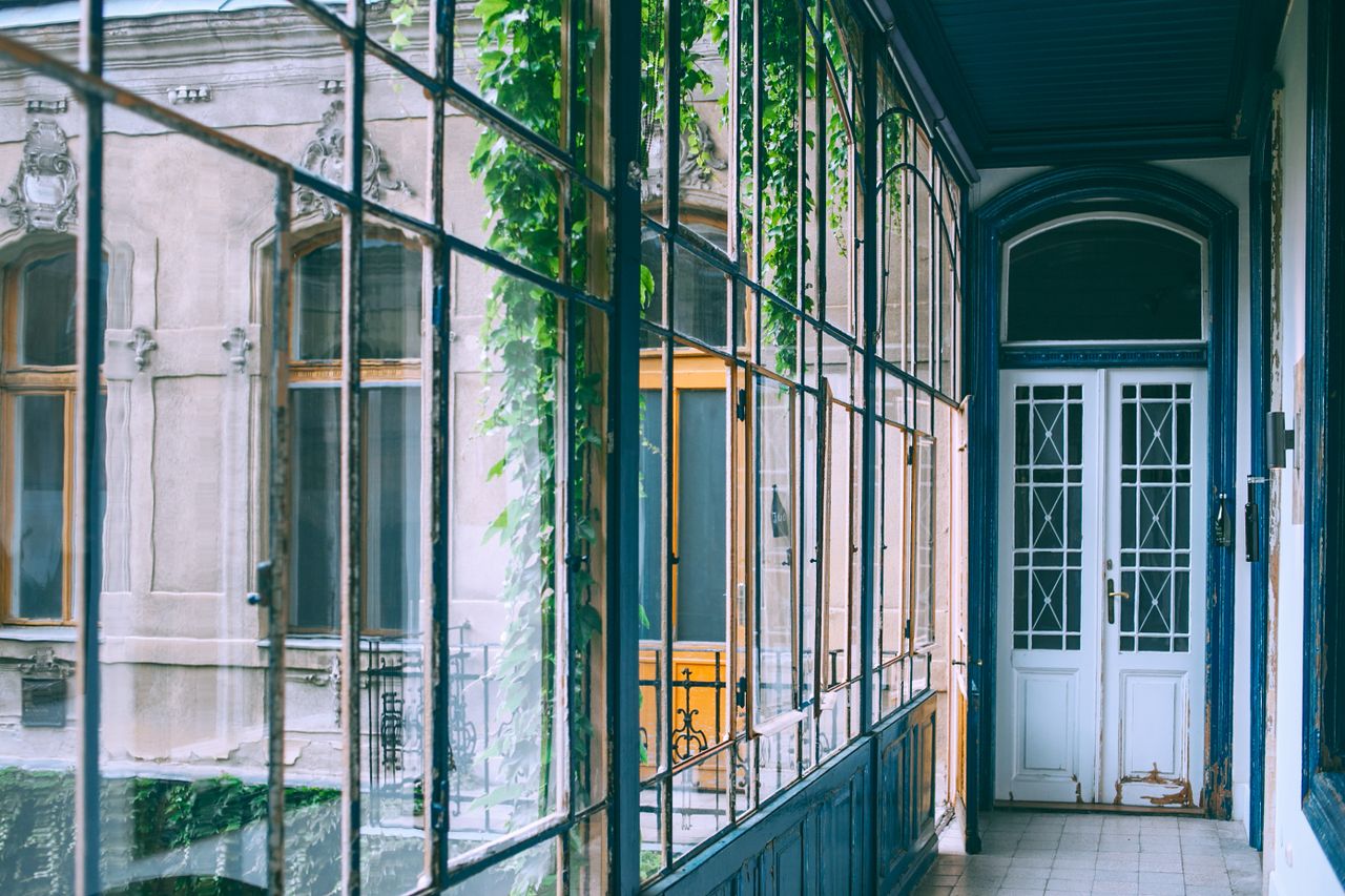 Interior of glass balcony with plants and classic wooden door in old building